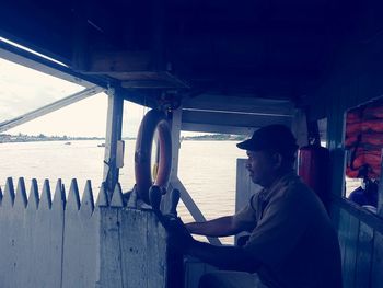 Side view of man in boat against sea