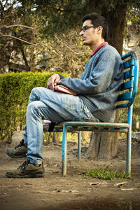 Side view of a young man sitting on bench