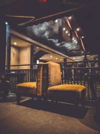 Empty chairs and tables in illuminated room at night