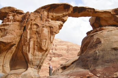 Rear view of man wearing traditional clothing standing on rock formations