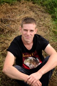 Portrait of young man sitting on field