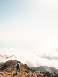 Rear view of man standing on mountain against sky