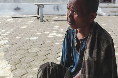 Man looking away while sitting on street