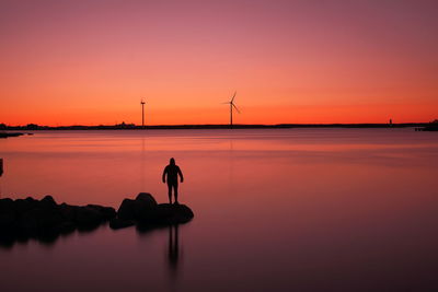 Silhouette of wind turbines against sky during sunset