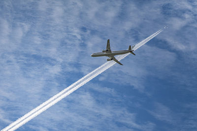 Low angle view of airplane against cloudy sky