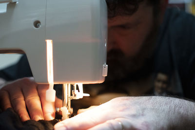 Man looking down while sitting with equipment in workshop