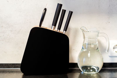 Modern black and white kitchen - black wooden stand for knives and transparent glass jug of water