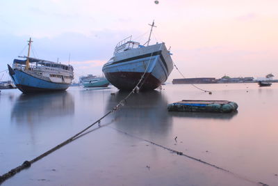 Fishing boats in sea at sunset