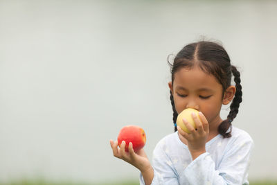 Portrait of girl holding apple against white background