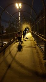 Rear view of people walking on illuminated footpath