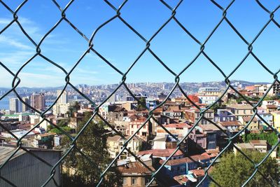 High angle view of cityscape seen through chainlink fence