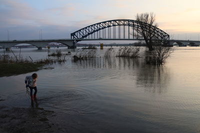 Man on bridge over river against sky