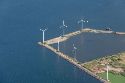 Windmills by sea against blue sky