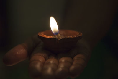 Close-up of hand holding lit candle