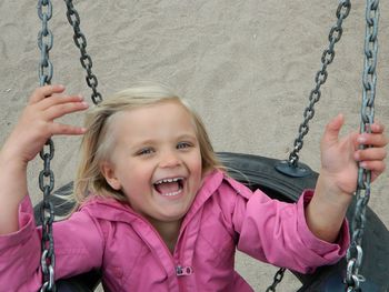 Portrait of smiling girl on swing at playground