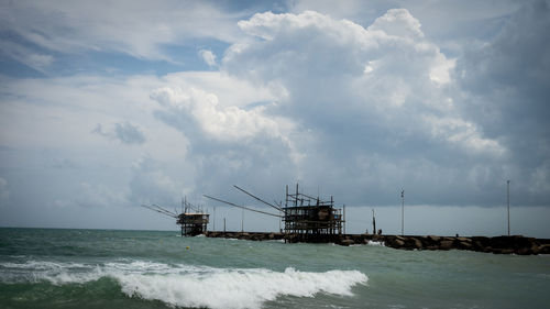 Cranes on pier over sea against sky