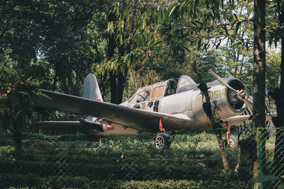 Abandoned airplane on field against trees