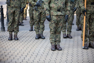 Polish soldiers stand at attention and one of them holds a flag pole.