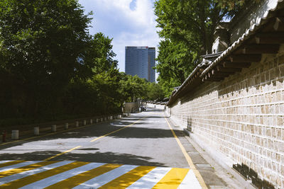Road amidst trees in city against sky