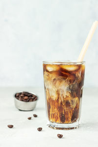 Iced coffee with milk in a tall glass with roasted coffee beans. summer refreshment drink. 