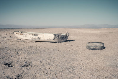 Abandoned motorcycle on sand at beach against sky