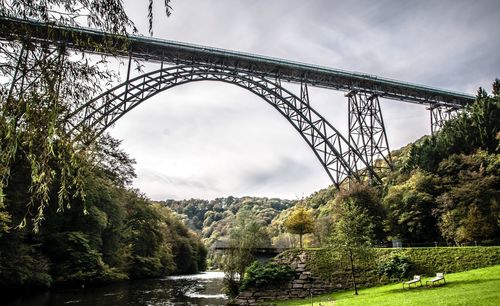 Low angle view of bridge over river against cloudy sky