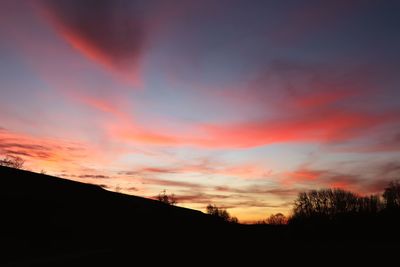 Silhouette landscape against dramatic sky during sunset