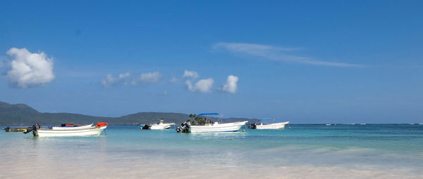 Boats moored in sea against blue sky
