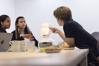 Business people discussing robot voice assistant during meeting