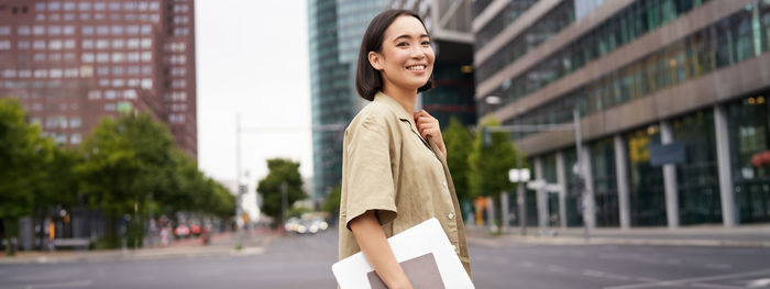 Portrait of young woman standing in city