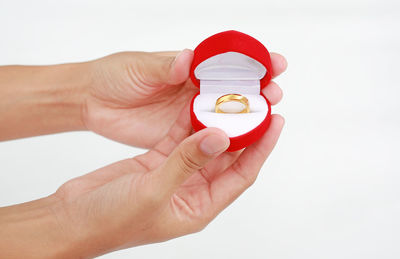 Close-up of human hand holding hat against white background