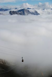 Overhead cable car over clouds and mountains
