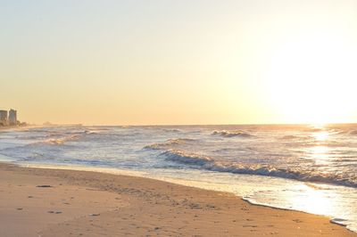Scenic view of beach against clear sky during sunset