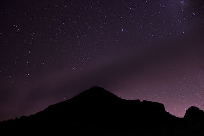Low angle view of silhouette mountain against sky at night with stars 