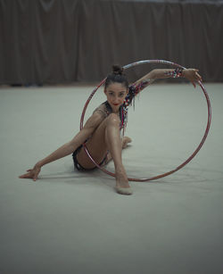 Portrait of woman dancing with plastic hoop on floor