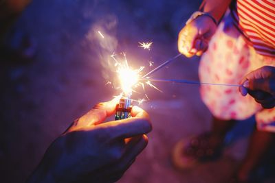 Cropped hand igniting sparklers held by girl