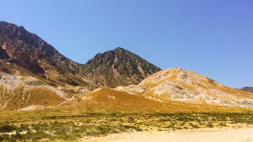 Scenic view of rocky mountains against clear sky on sunny day