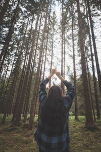 Rear view of woman standing in forest