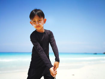 Boy standing on beach against sky