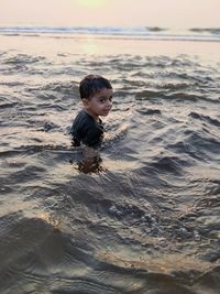 Boy swimming in sea against sky