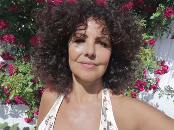 Portrait of smiling beautiful woman against red flowering plants