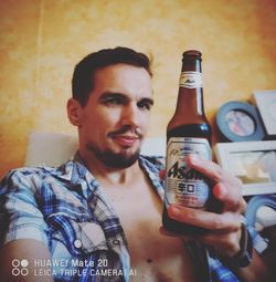 Portrait of young man drinking beer in glass