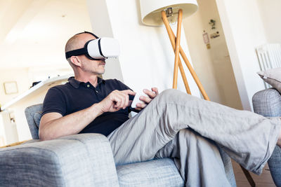 Midsection of man using mobile phone while sitting on sofa at home
