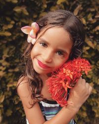 Close-up portrait of smiling girl holding flowers