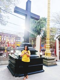 Full length of woman standing against cross