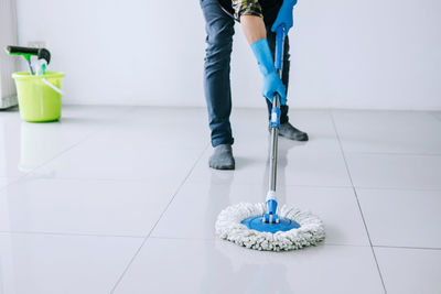 Low section of man moping on floor at home