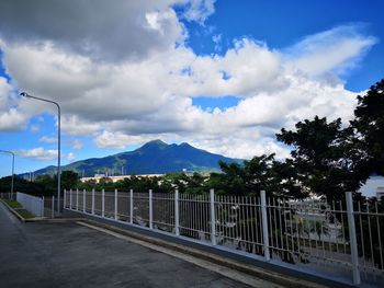 Road by plants and mountains against sky