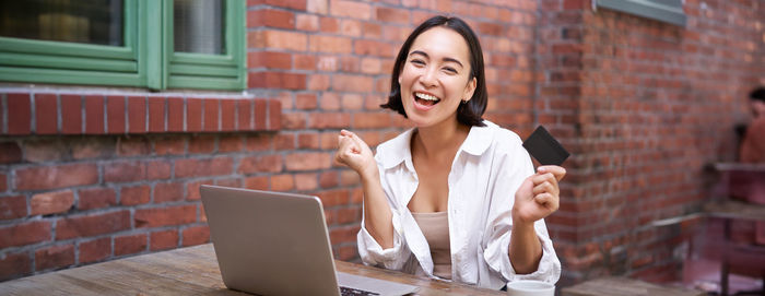 Young woman using laptop while sitting on table