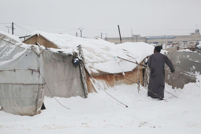 A refugee  clears his tent of snow that has devastated syrian refugee camps near the turkish border.