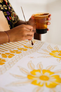 Midsection of woman making batik at workshop